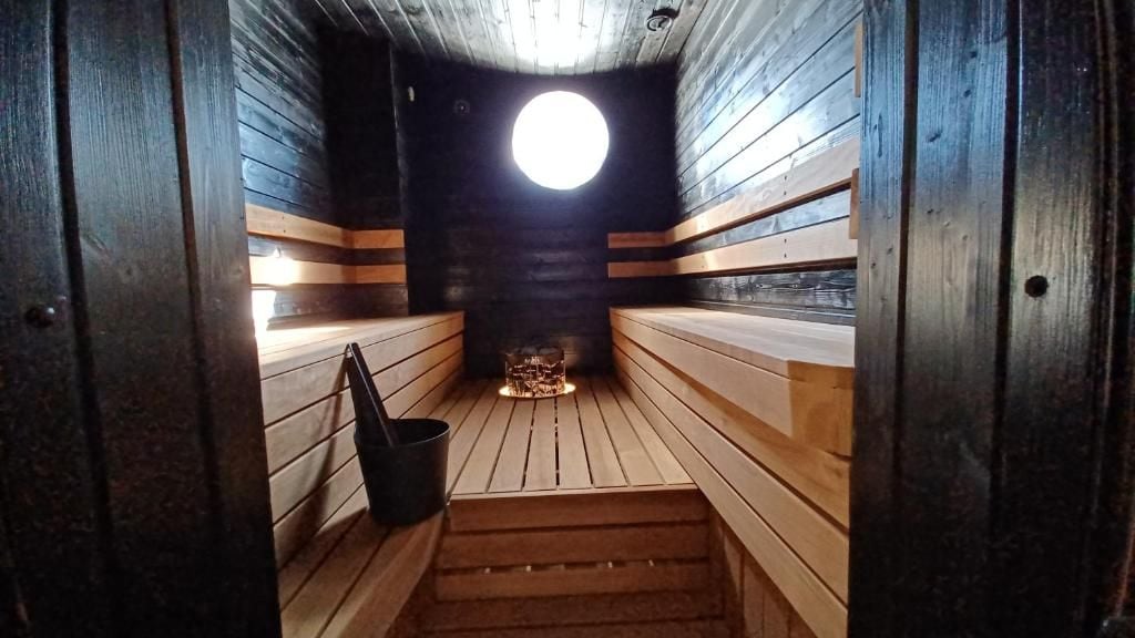 A sauna with wooden benches and a central heater.