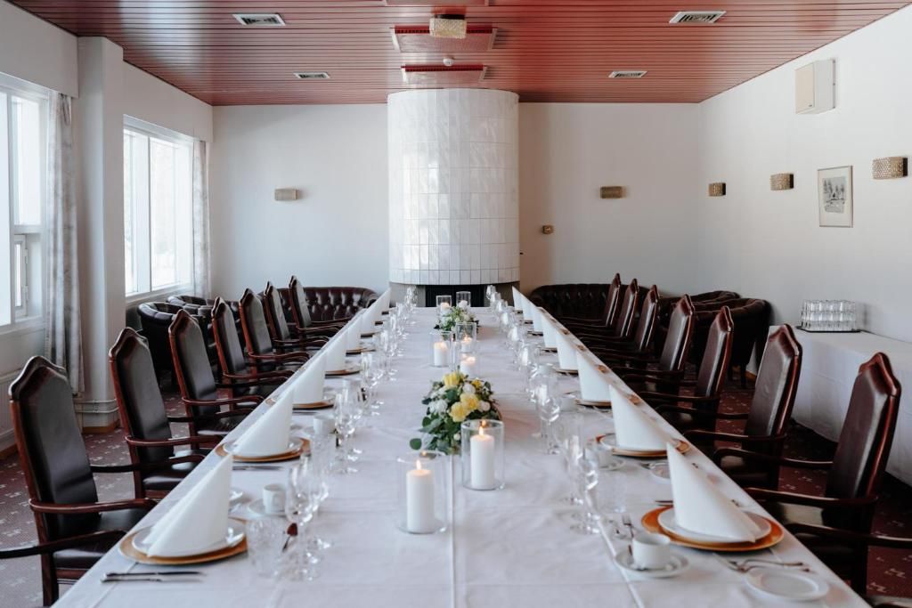 A long dining table set for a formal event, surrounded by chairs, with a decorative centerpiece and candles.