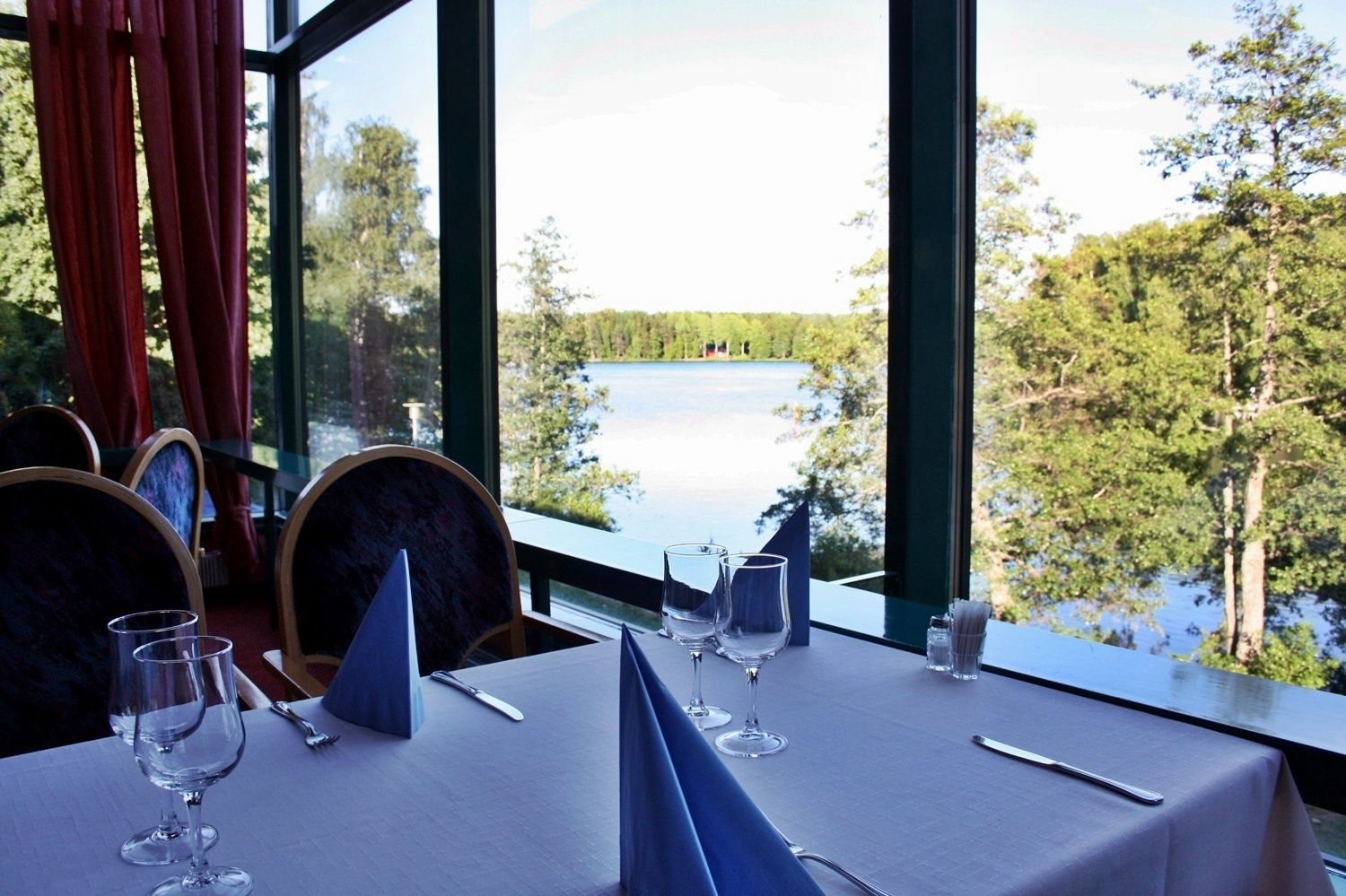 A table set for dining with a view of a lake and forest.