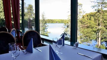 A table set for dining with a view of a lake and forest.