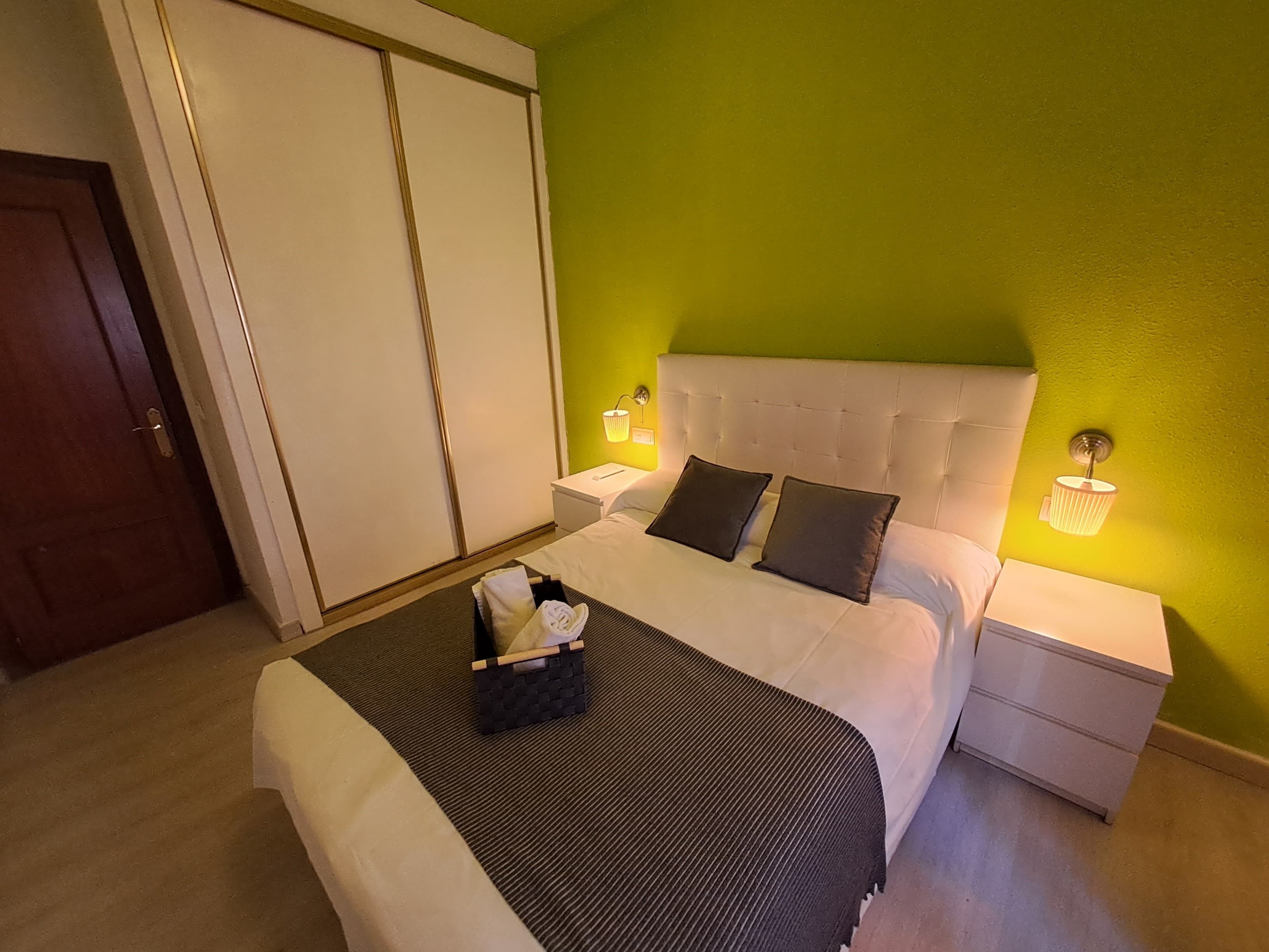 A hotel room with a bed, nightstands, a wardrobe, and a green wall.
