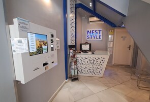 Zona de recepción de hotel con un letrero tipo Nest, un quiosco de autoservicio y una encimera con diseño estampado.