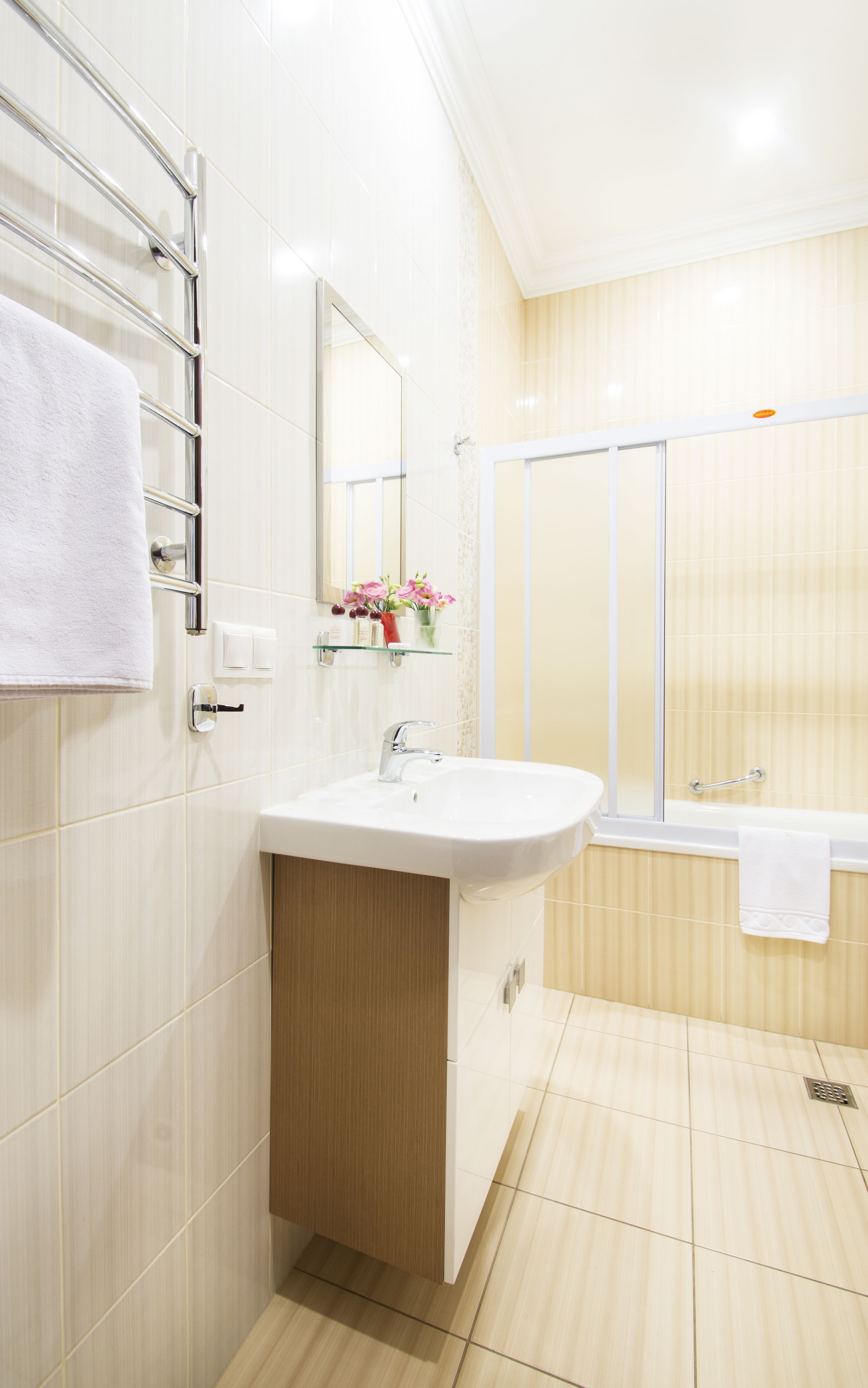 A modern bathroom with a white sink, mirror, and glass shower enclosure.