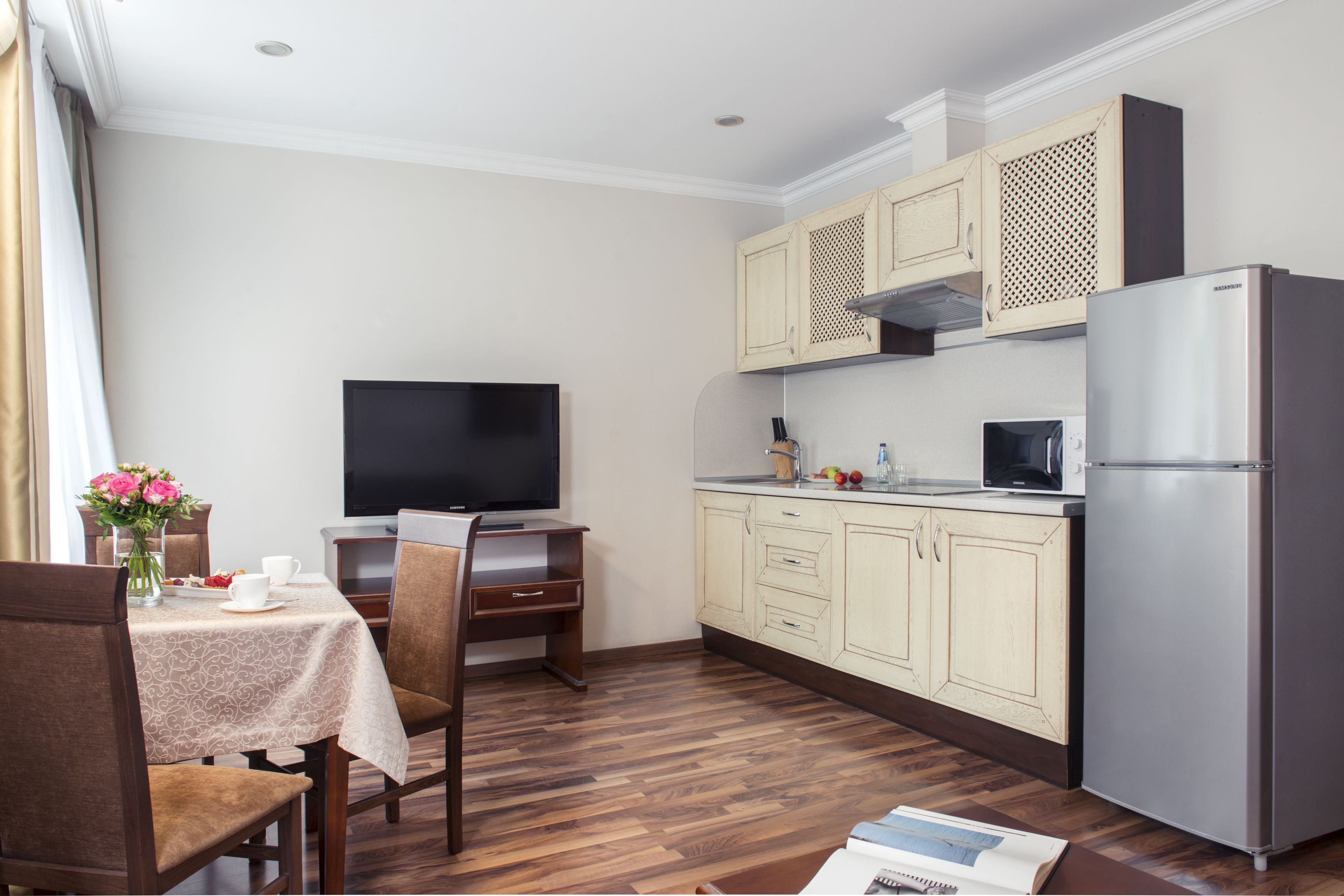 A compact kitchen with wooden cabinets, a built-in microwave, and a refrigerator.