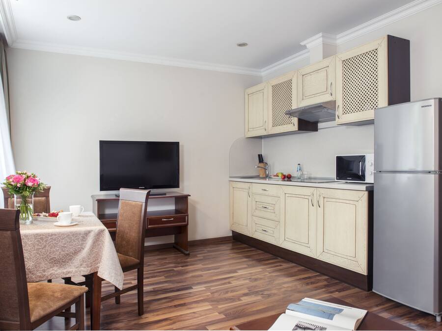 A compact kitchen with wooden cabinets, a built-in microwave, and a refrigerator.