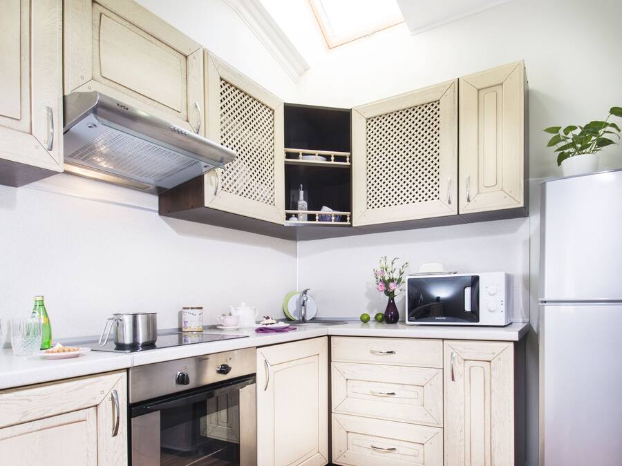 A kitchen with wooden cabinets, a microwave, a refrigerator, and a skylight.
