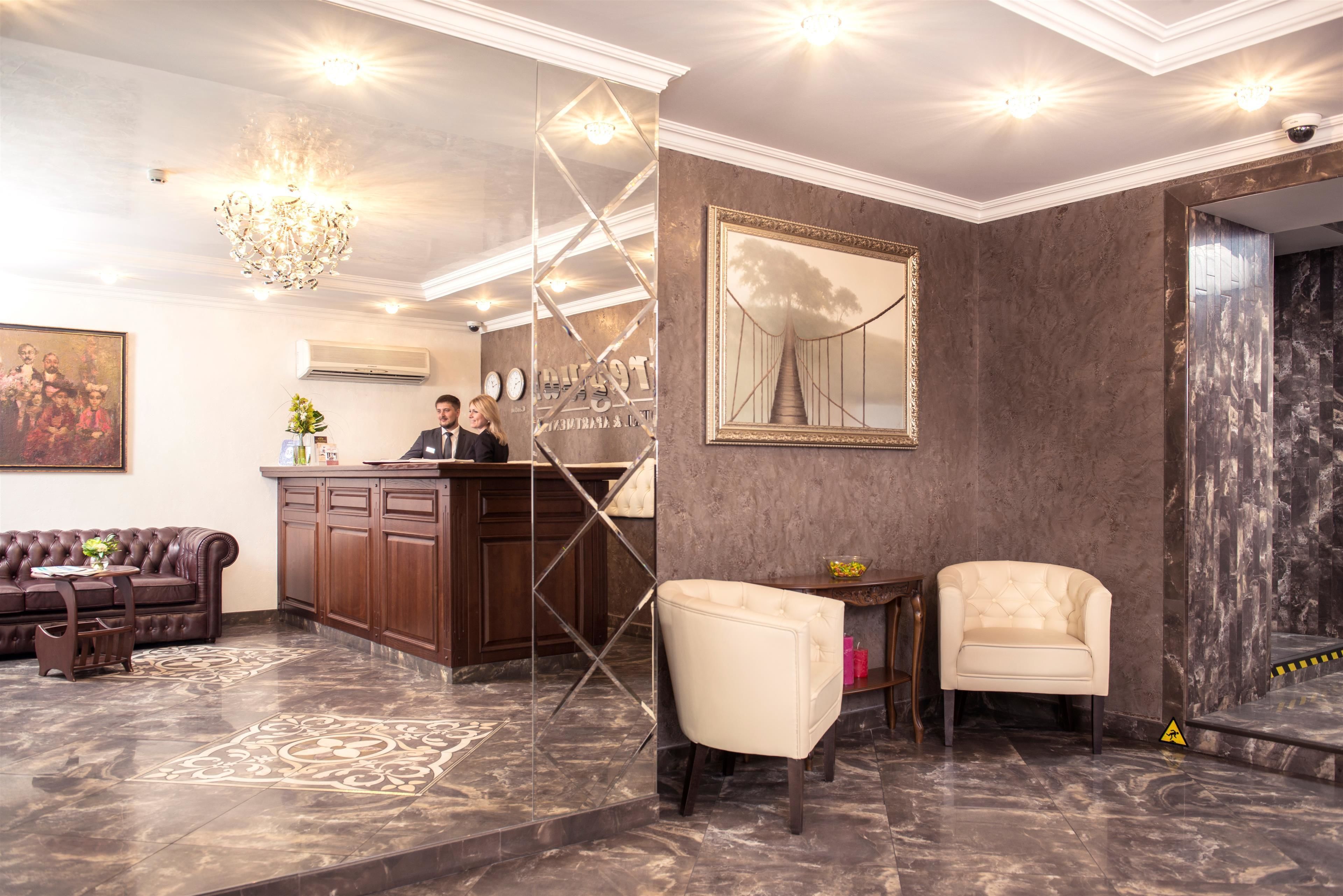 A lobby with a reception desk, a sofa, a chair, and a chandelier.