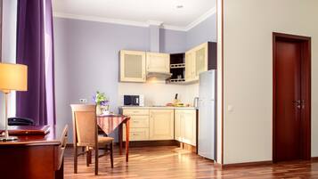 A compact kitchen with wooden cabinets, a dining table with chairs, and a refrigerator.