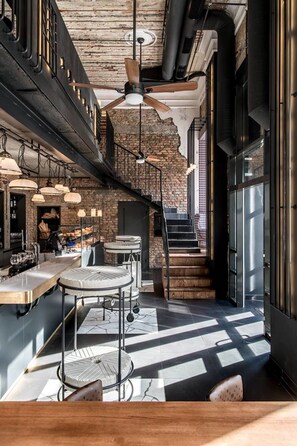 A modern kitchen with a brick wall, a wooden staircase, and a dining area with a black and white checkered floor. - Greguar Hotel & Apartments (Kyiv)
