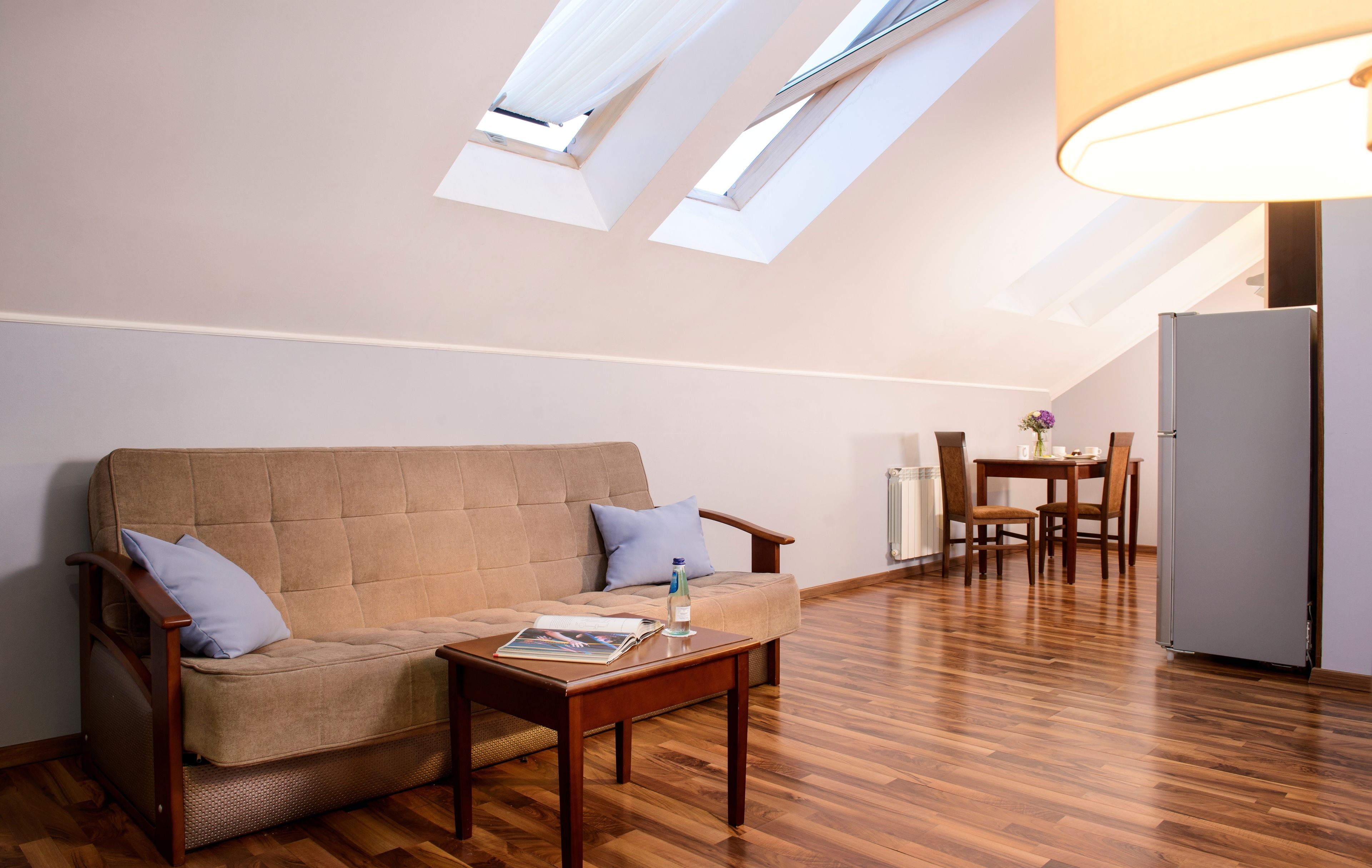 Ein gemütliches Loft mit einer Couch, einem Esstisch und einem Kühlschrank.