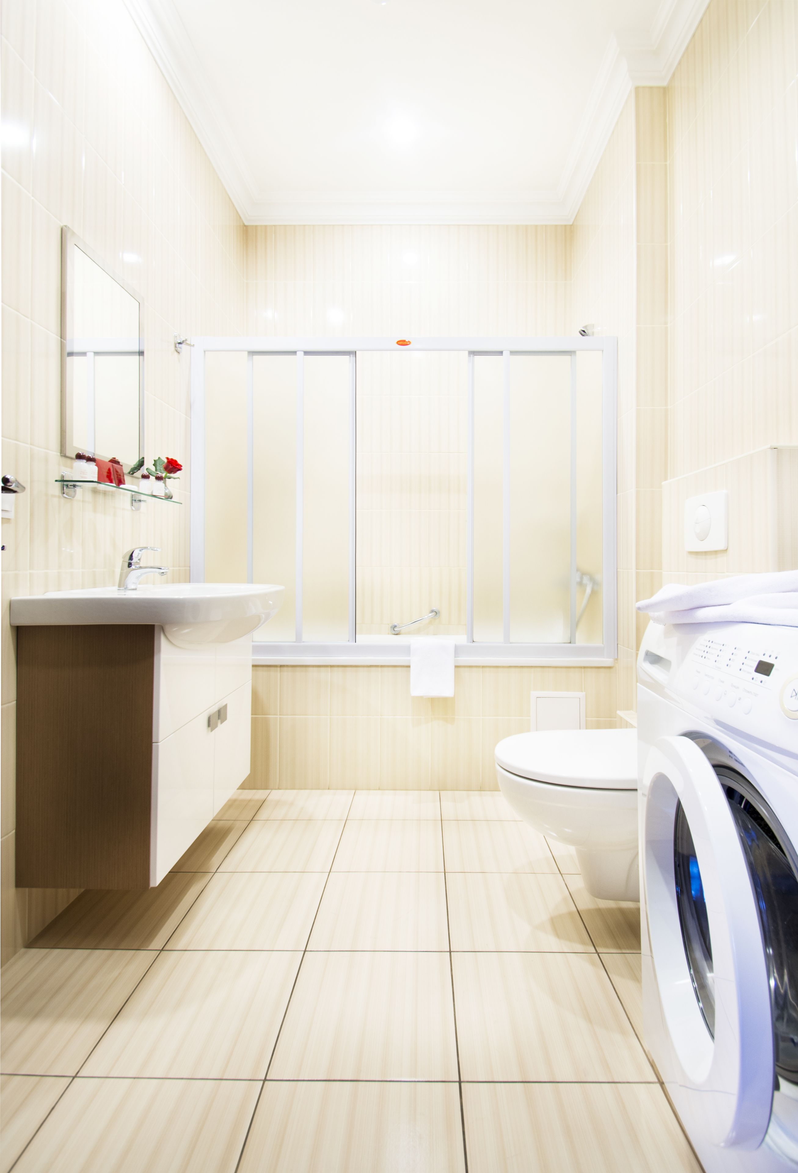 Een moderne badkamer met een wastafel, spiegel, toilet en een wasmachine.