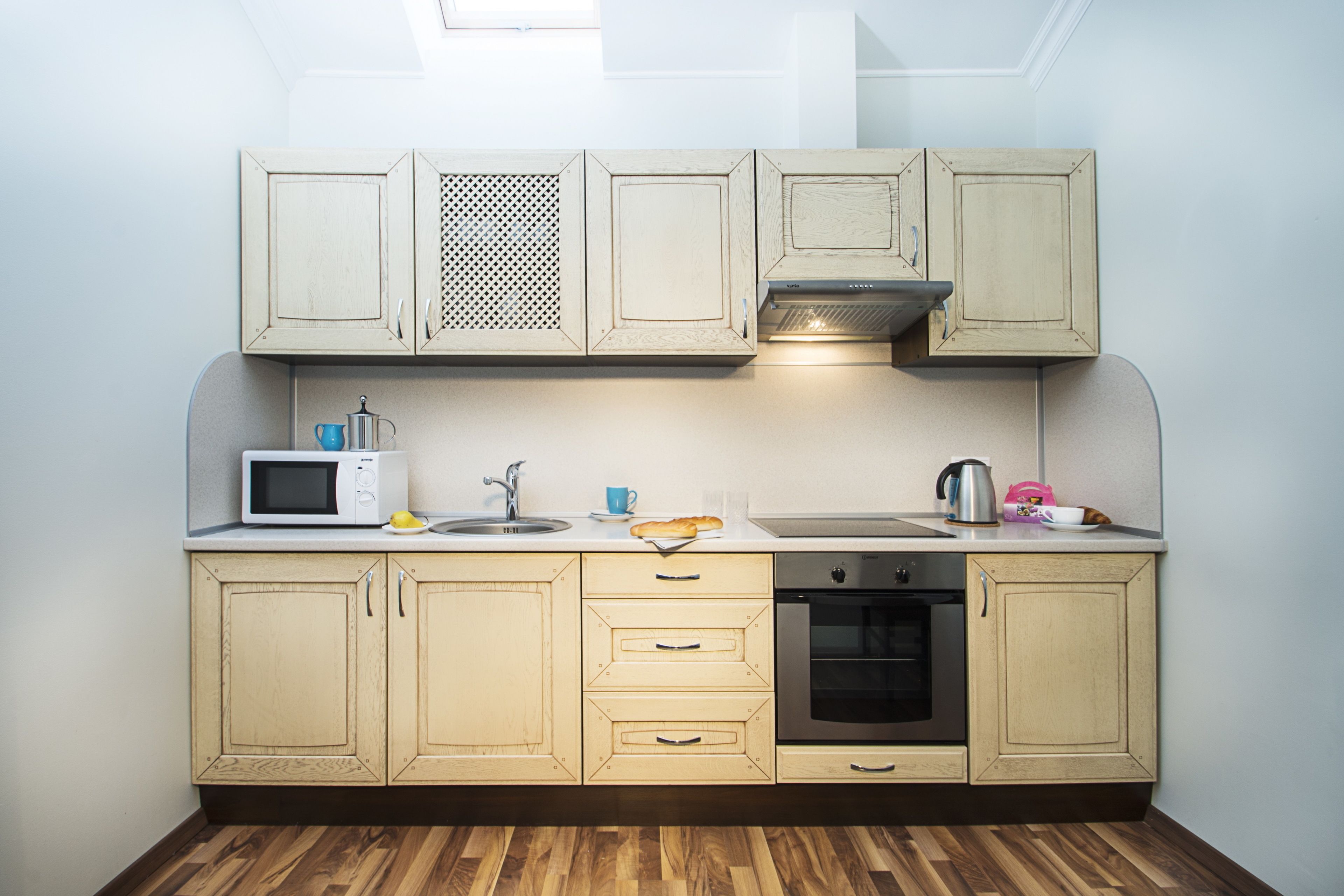 A compact kitchen with wooden cabinets, a microwave, a sink, and an oven.