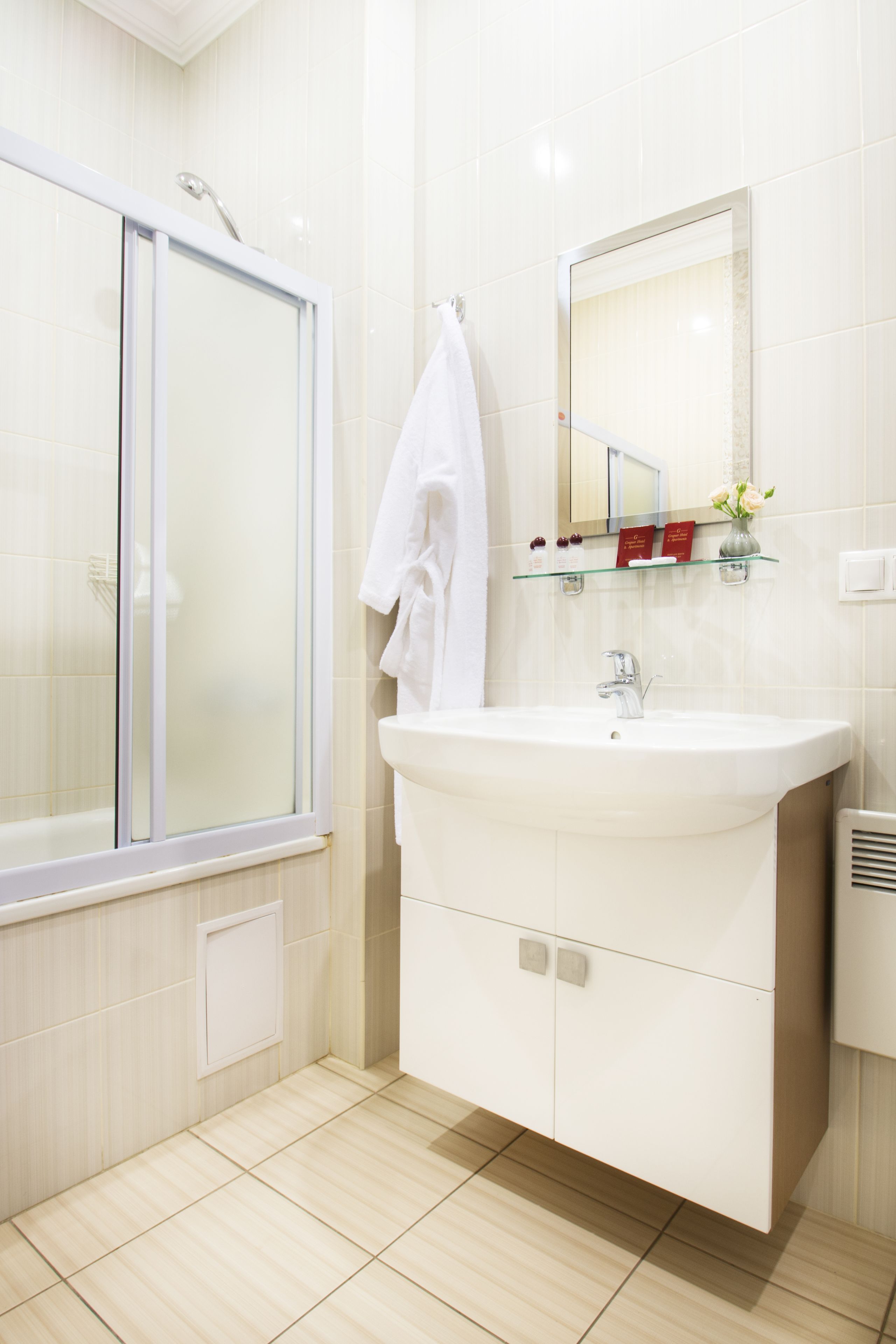 Une salle de bain moderne avec une douche à l’italienne en verre, un lavabo blanc et un miroir au-dessus.