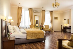 A hotel room with a large bed, two armchairs, a desk, and a chandelier. - Greguar Hotel & Apartments (Kyiv)