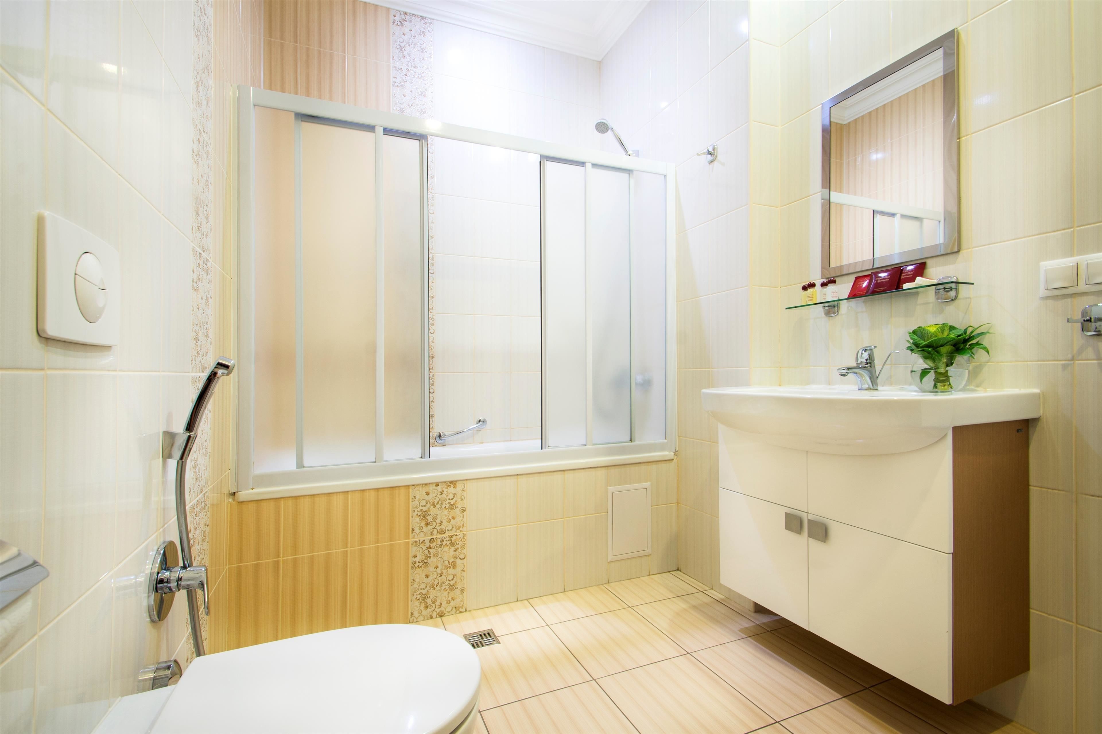 A modern bathroom with a glass-enclosed shower, a white sink, and a mirror above the sink.