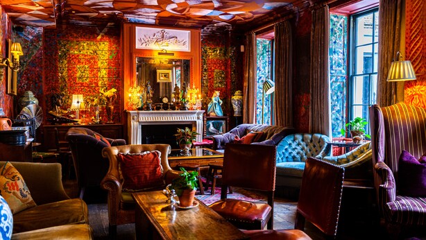 A cozy room with a fireplace, plush seating, and a large window with curtains. - The Zetter Clerkenwell (London)