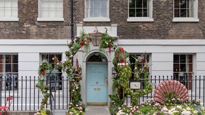 A building facade with a blue door, a black metal fence, and a red chair. - The Zetter Clerkenwell (London)