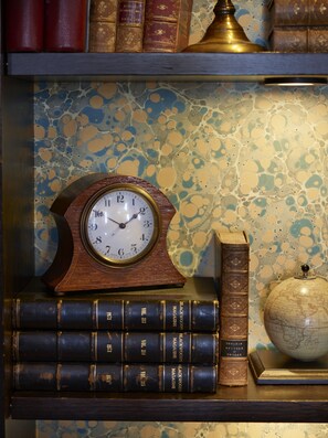 Una estantería de madera con un reloj, libros y un globo terráqueo.