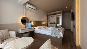 Une chambre d’hôtel comprenant un lit, une table ronde, un canapé, un miroir et un appareil de climatisation.