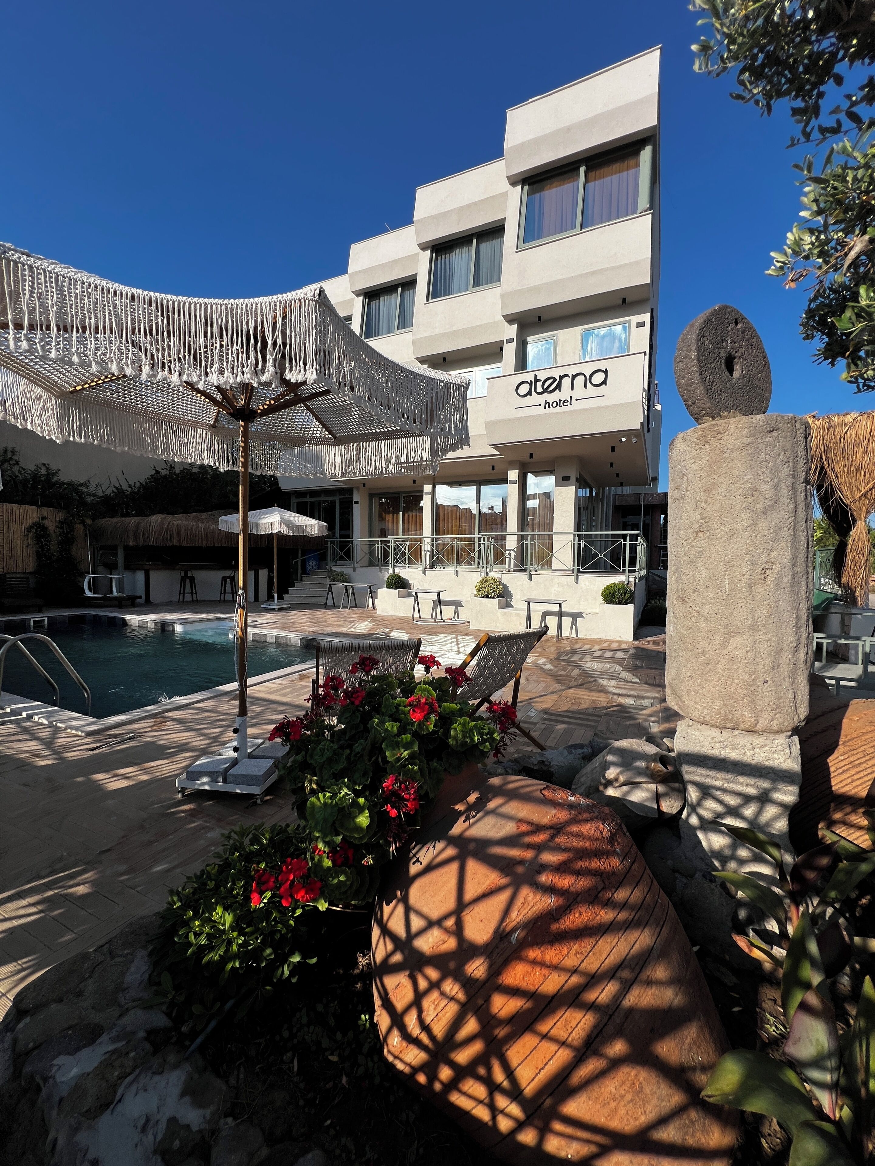 Un hotel con piscina, mobiliario exterior y una escultura de piedra.