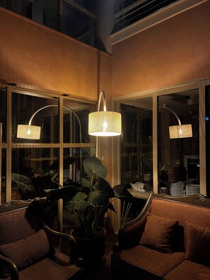 A modern interior with a sofa, potted plants, and two hanging lamps. - Aterna Hotel (Dikili)