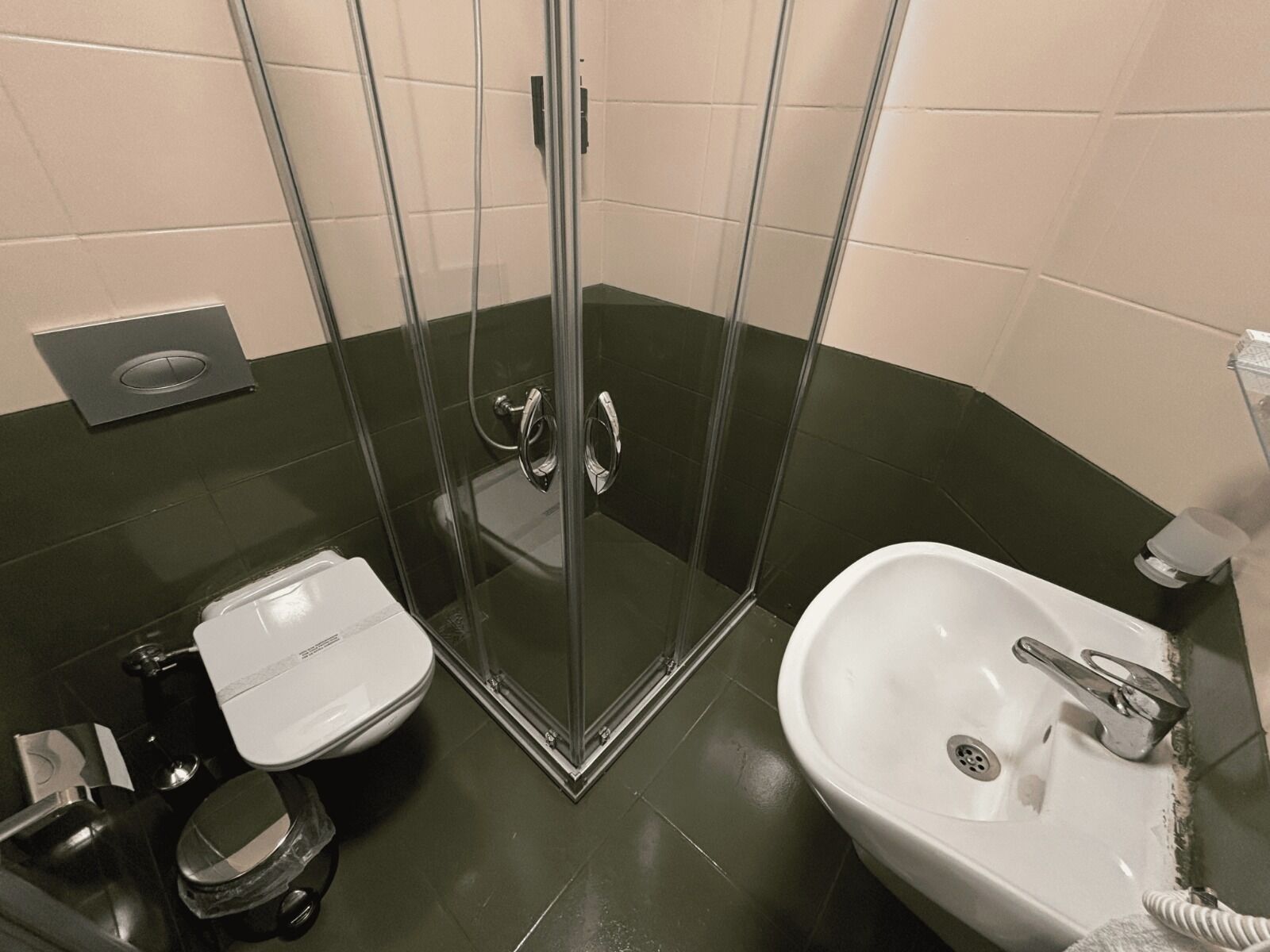 A bathroom with a glass-enclosed shower, a toilet, and a sink.