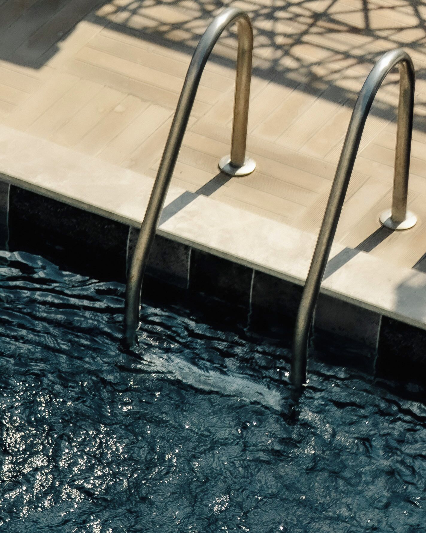 A swimming pool with metal ladders and a tiled deck.