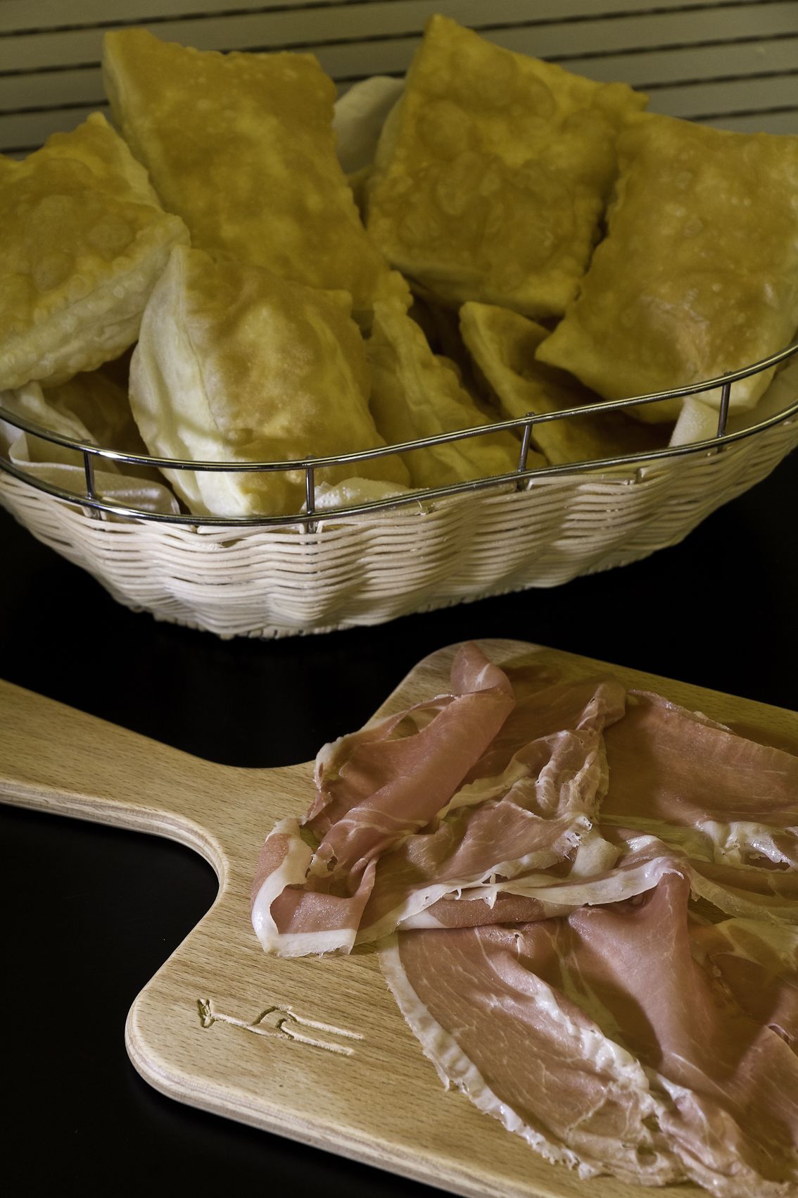 Un panier de pain et une planche à découper en bois avec de la viande tranchée.