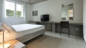 Een moderne slaapkamer met een bed, nachtkastje, televisie en een stoel.