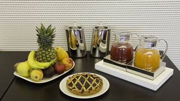 Un tavolo con un piatto di frutta, una crostata e un vassoio con una brocca e delle tazze.
