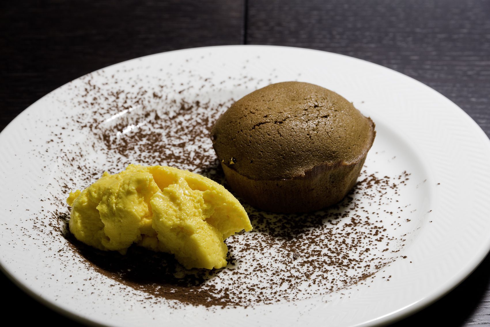 Un postre sobre un plato blanco, espolvoreado con cacao.