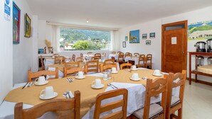Comedor con varias mesas dispuestas para el desayuno, sillas de madera y vistas al exterior.