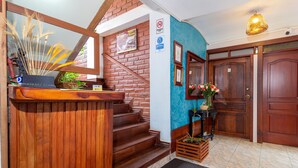 Un mostrador de recepción de madera con un espejo, una escalera, una pared azul decorativa y una puerta de madera.