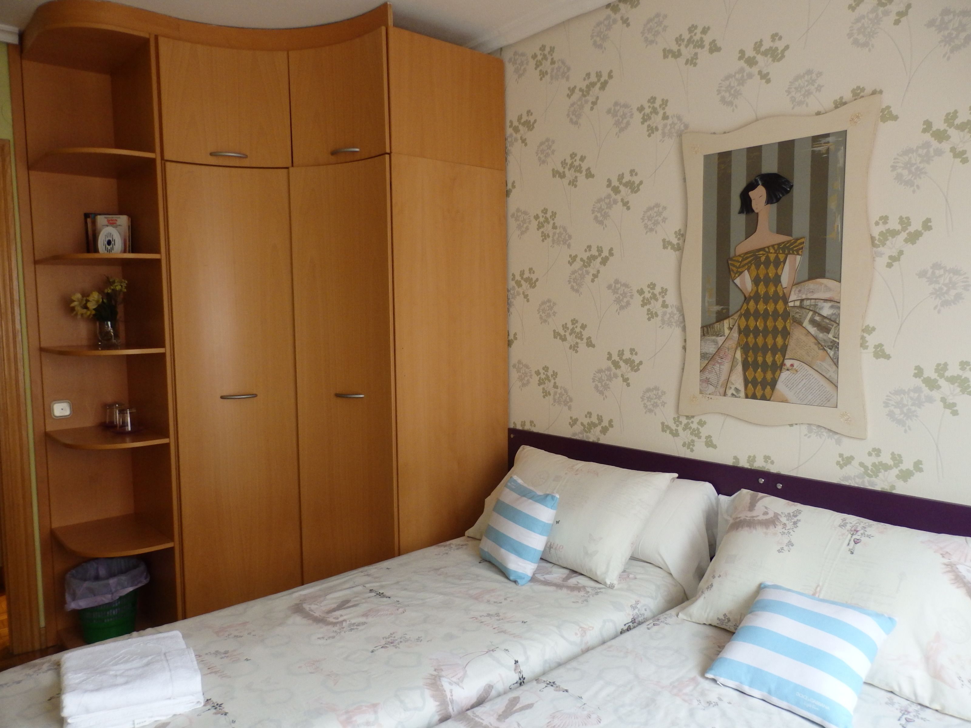 A bedroom with a bed, a wardrobe, and a mirror on the wall.