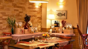 A restaurant with checkered tablecloths, wooden chairs, and a brick wall. - Relais Concorde (Grottammare)