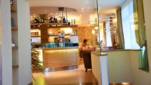 A modern bar area with shelves of bottles, a coffee machine, and a glass display case. - Relais Concorde (Grottammare)