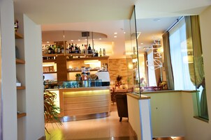Una zona de bar moderna con estantes llenos de botellas, una cafetera y una vitrina de vidrio.