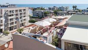 A rooftop terrace with outdoor seating, a view of the sea, and surrounding residential buildings. - Relais Concorde (Grottammare)