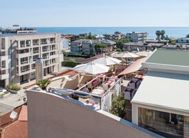 Terraza en la azotea con mobiliario exterior, vista al mar y edificios residenciales circundantes.