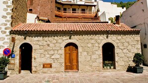 A stone building with a wooden door and two arched windows, a sign indicating a hotel, and a small balcony. - Hotel Rural Fonda de la Tea (Tejeda)