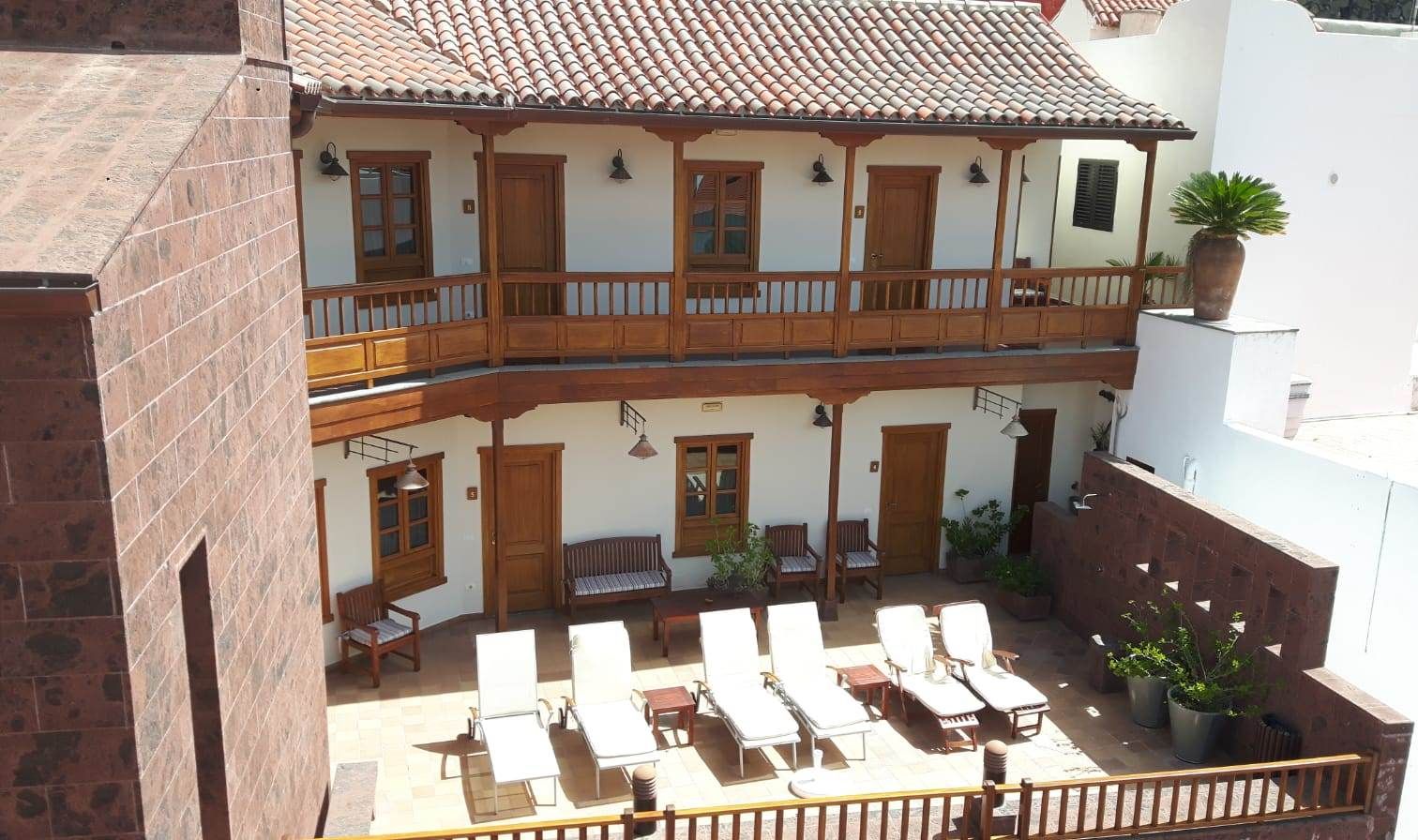 A two-story building with a balcony, outdoor seating area, and potted plants.