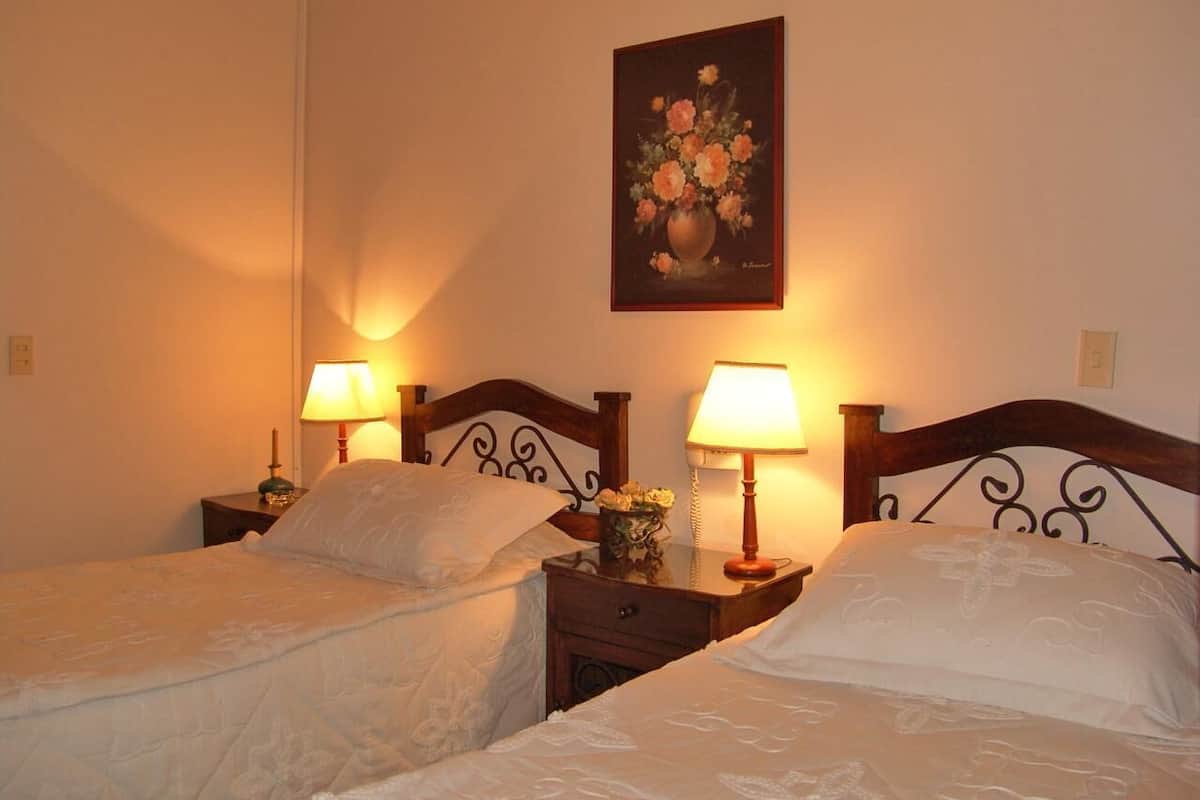 Ein Doppelbett mit zwei Nachttischen, jeweils mit einer Lampe und einer kleinen Blumenvase.