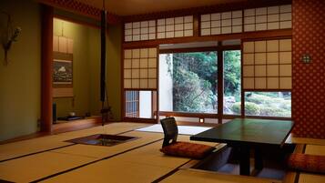 A traditional Japanese tatami room with tatami mats, a low table, and a sliding door leading to a garden.