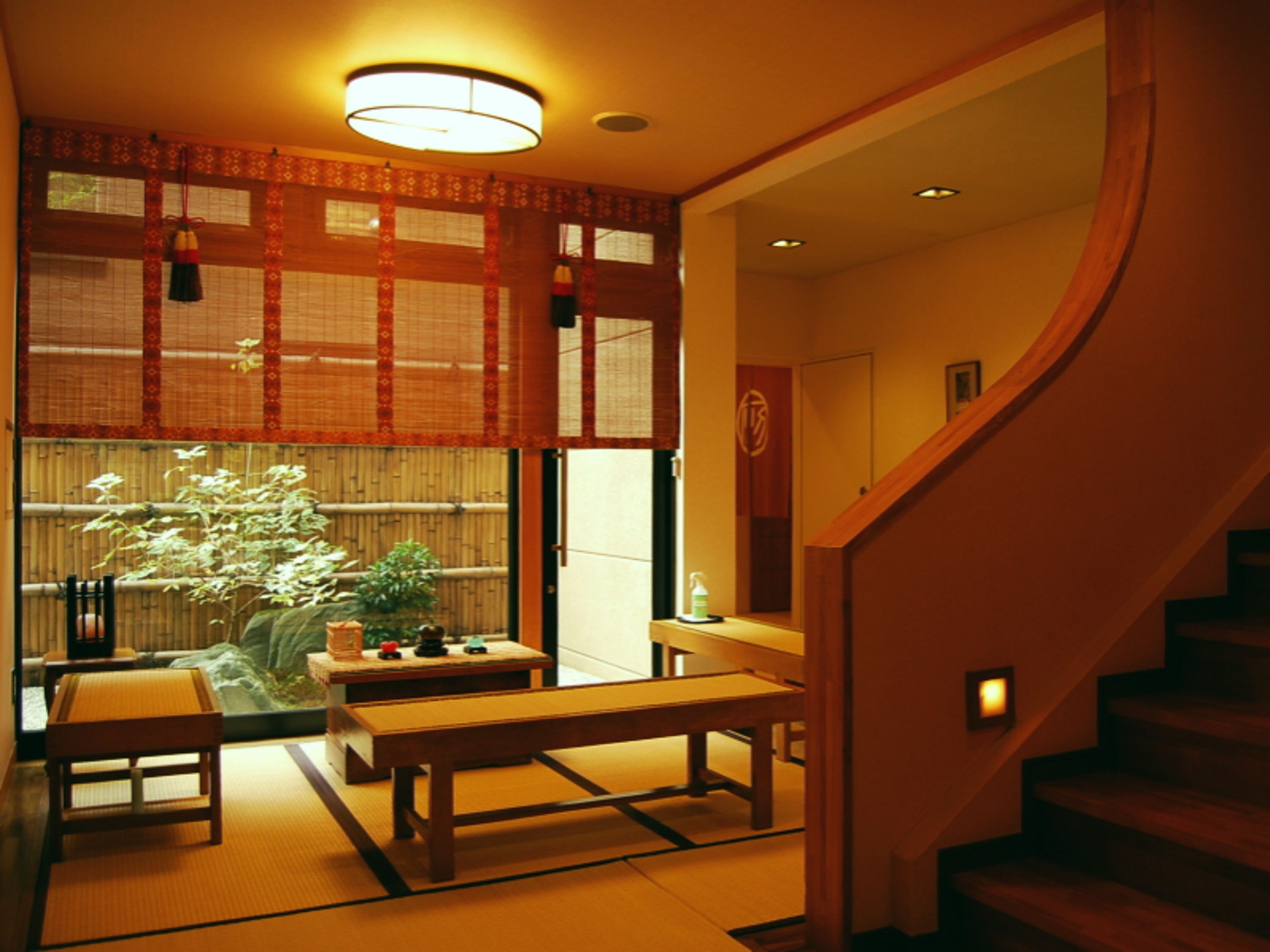 A traditional Japanese room with tatami flooring, a low table, a bench, and a shoji screen door.