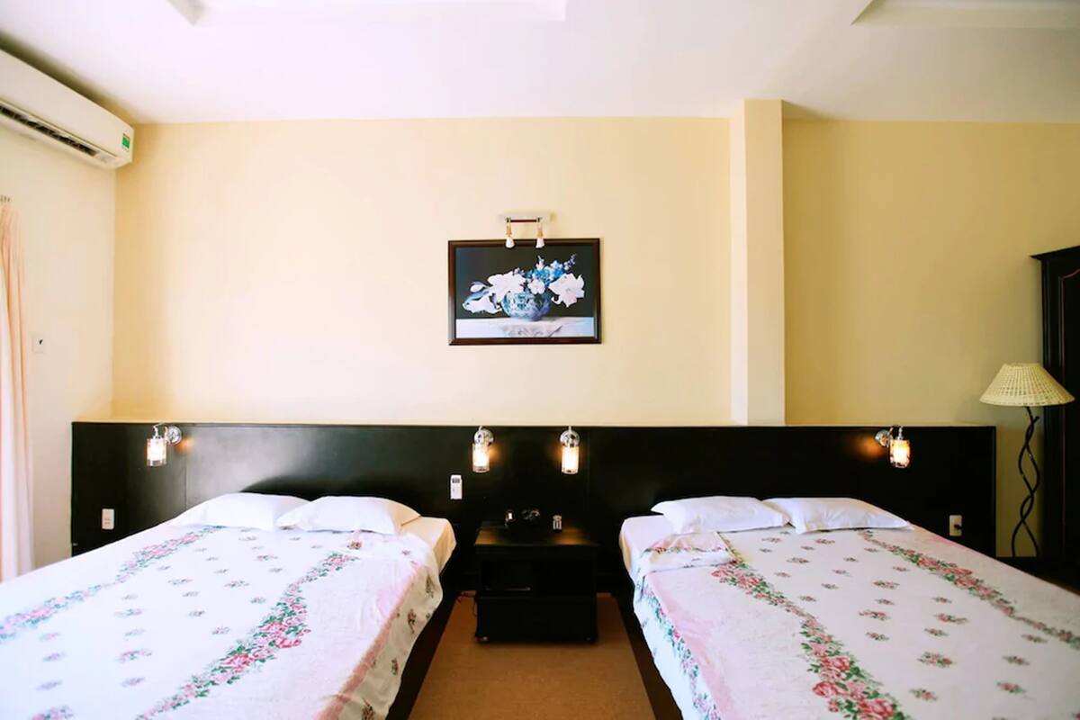 Habitació d'hotel amb dos llits, una nit, un quadre penjat a la paret i una làmpada.