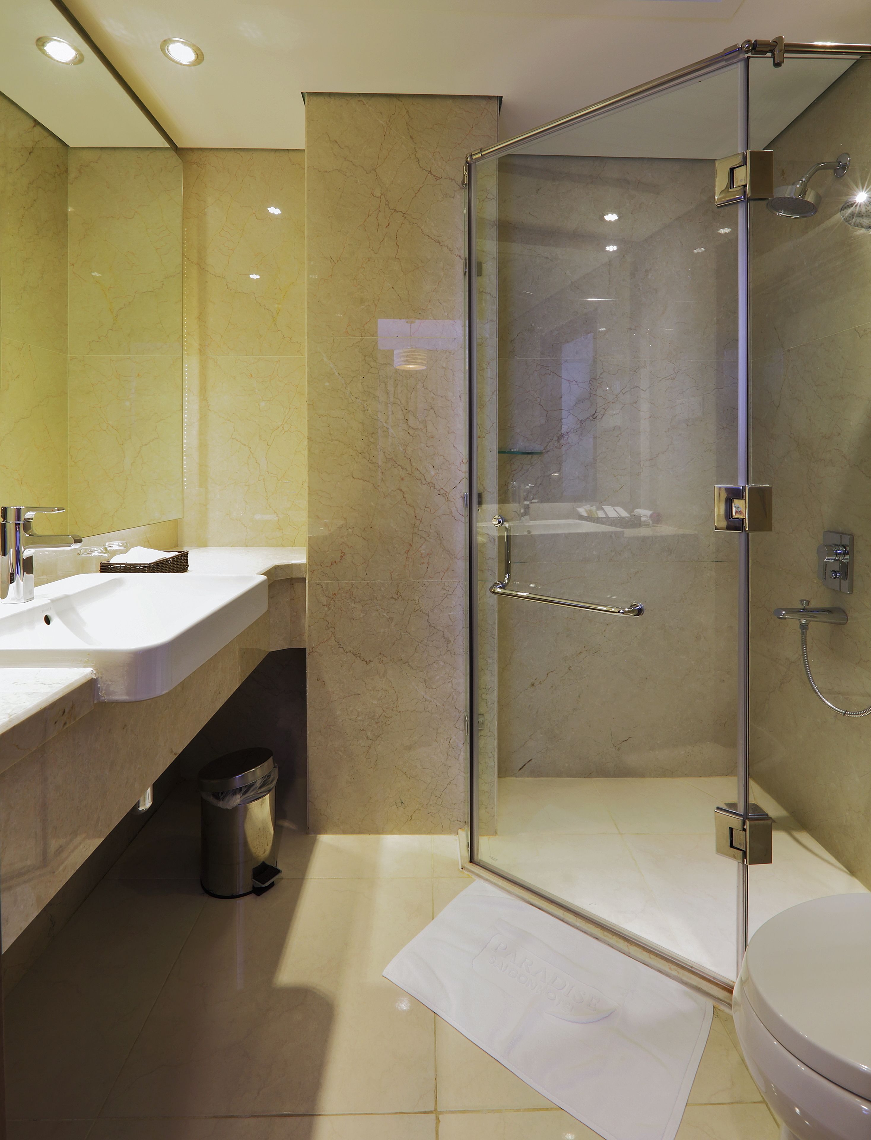 A modern bathroom with a glass-enclosed shower, a white sink, and a toilet.