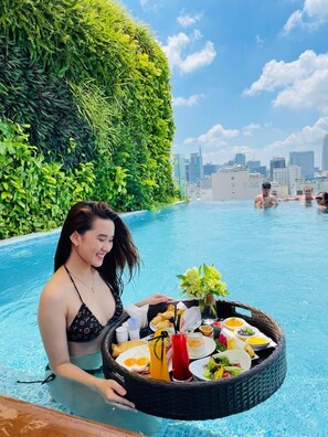 Una persona en una piscina sosteniendo una cesta con comida y bebidas.