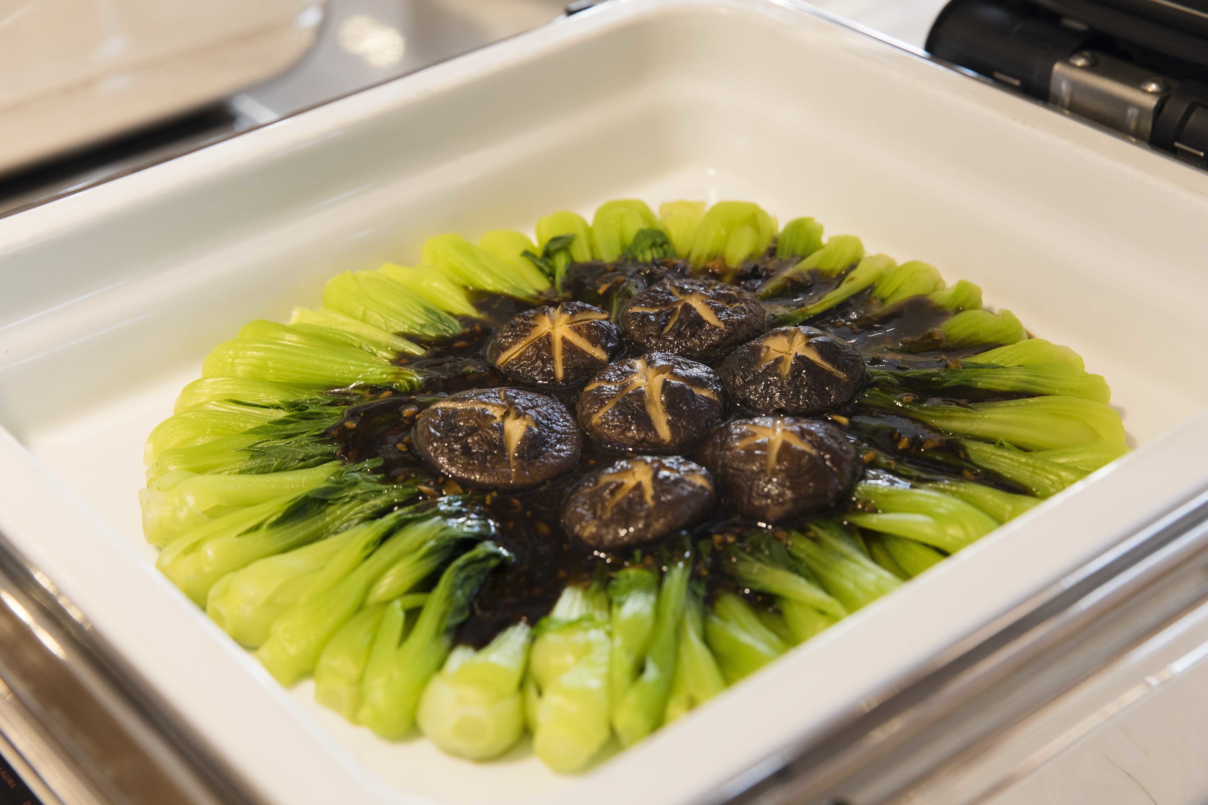 Un piatto di funghi e bok choy su un piatto bianco.