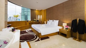 Habitación de hotel moderna con una cama grande, un área de estar, un escritorio y vistas a la ciudad.