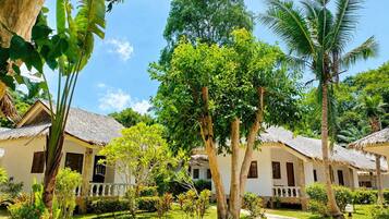 Un resort tropical con cabañas de techo de paja, exuberante follaje y cielo despejado.